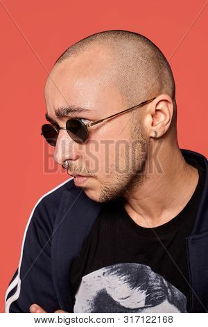 Studio Shot Of A Young Tattoed Bald Man Posing Against A Pink Background. 90s Style.