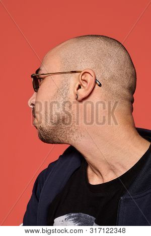 Studio Shot Of A Young Tattoed Bald Man Posing Against A Pink Background. 90s Style.