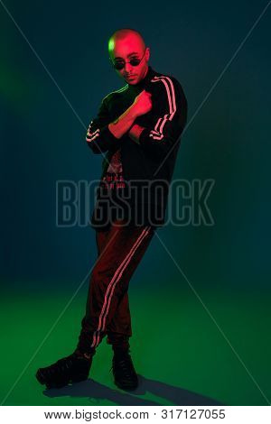 Studio Shot Of A Young Tattoed Bald Man Posing Against A Colorful Background. 90s Style.