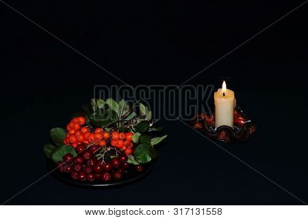 Beautiful Original Candlestick With Lit Candle And Branches Of Red And Black Rowan Berries On Black 