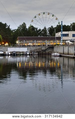 Vertical Frame, Beautiful Port City With A Ferris Wheel, Evening View With Reflection In The Water.
