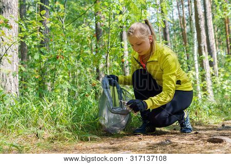 Woman Runner Puts Litter In A Garbage Bag During Plogging In The Park