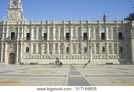 Leon, Spain - June 26th, 2019: Biker Pilgrim Walking Beside Convent Of San Marcos At Leon City Going