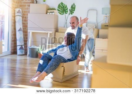 Funny and crazy couple having fun riding a cardboad box as a car, smiling happy and lauging at new home