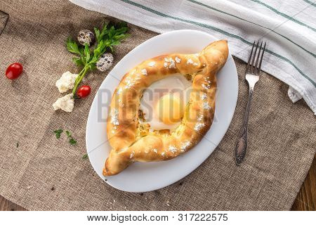 Adjarian Khachapuri Traditional Georgian Dish With Sulguni Cheese Filled Bread And Egg Yolk On Table