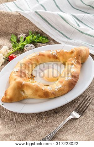 Adjarian Khachapuri Traditional Georgian Dish With Sulguni Cheese Filled Bread And Egg Yolk On Table