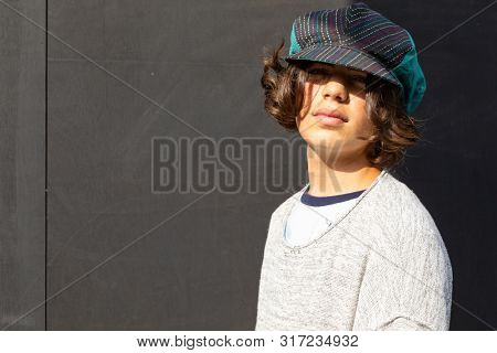 Portrait of boy with colorful hat and black background.