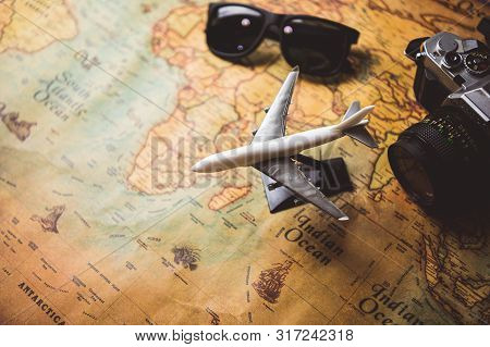 Tourist Planning Props And Travel Accessories With Airplane, Digital Camera And Sunglasses On Old Gr