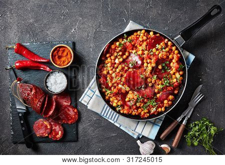 Garbanzos Fritos, Fried Chickpeas With Chorizo, Ham Tomatoes And Spices In A Skillet On A Concrete T