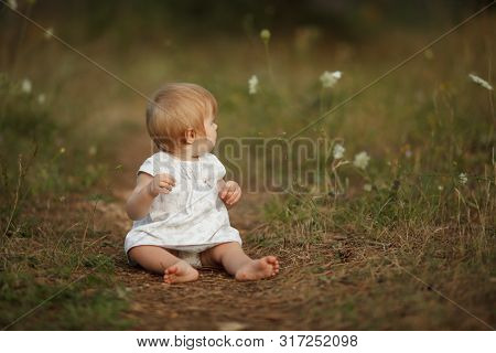 Cute Little Baby Girl Sitting On The Path In The Forest. Turned Away From Camera. The Concept Is Ten