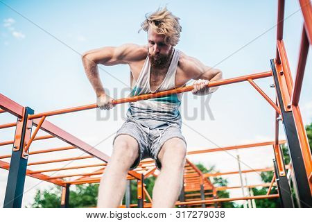 Strong Athlete Doing Pull-up On Horizontal Bar. Muscular Man Doing Pull Ups On Horizontal Bar In Par