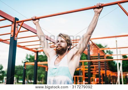 Strong Athlete Doing Pull-up On Horizontal Bar. Muscular Man Doing Pull Ups On Horizontal Bar In Par