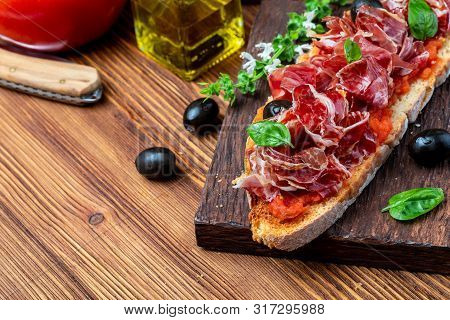 Delicious Bread Toast With Natural Tomato, Extra Olive Oil, Iberian Ham, Black Olives And Basil Leav