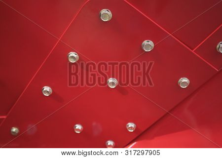 Close Up Of Bolts And Nuts On Iron Wall Painted In Red.