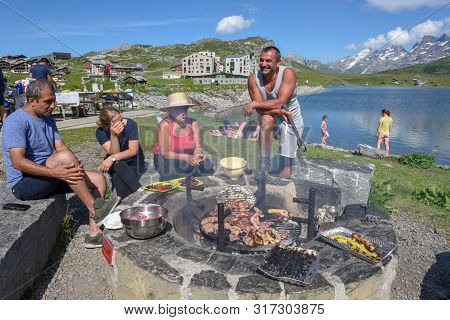 Group Of Happy People Frying Meet On Barbeque Grill At Melchsee-frutt On The Swiss Alps