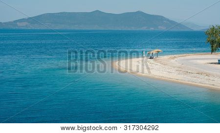 Empty Beach On A Greek Island With One Sunshade