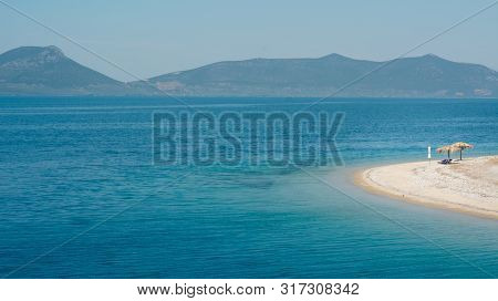 Empty Beach On A Greek Island With One Sunshade
