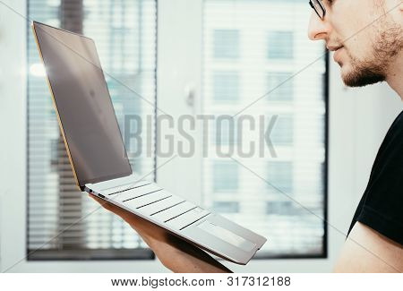 Young Freelancer Is Holding Up A Thin Elegant Notebook