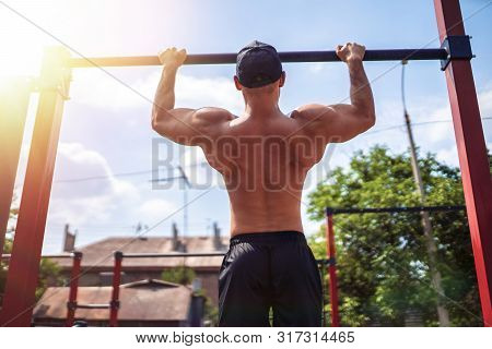 Brutal Athletic Man Making Pull-up Exercises On A Crossbar At Outdoor Streeet Gym. Back View.