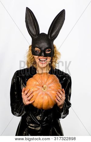 Beautiful Woman In Halloween Bunny Costume Holds Pumpkin. Sexy Blonde Girl In Rabbit Black Mask With