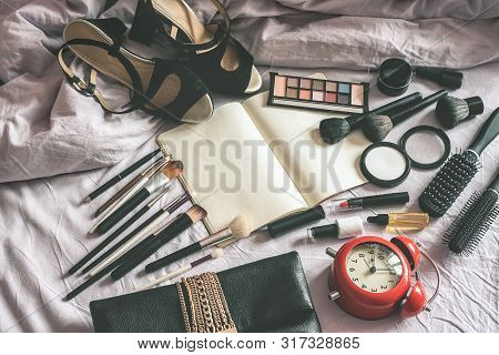 Make Up Cosmetic And Brushes, Alarm Clock And Blank Page Notepad On The Blanket On The Bed Backgroun