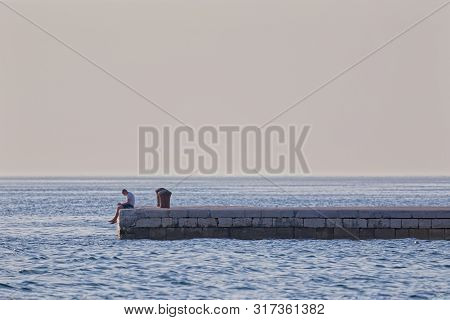 Zadar, Croatia - April 29, 2018: Man Watching His Cell Phone At The Dock At Obala Kralja Petra Kresi