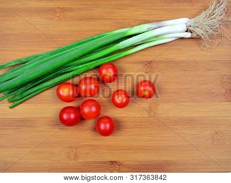 Fresh Red Cherry Tomatoes And Green Spring Onion On Wooden Background