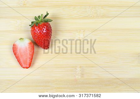 Fresh Juicy Strawberry And A Slice Cut Isolated On Wood Background