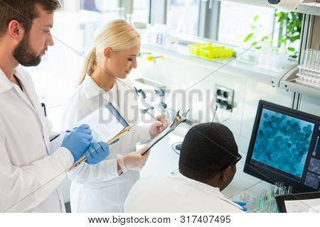 Scientist and students working in lab. Doctor teaching interns to make blood analyzing research. Biotechnology, chemistry, bacteriology, virology and health care concept.