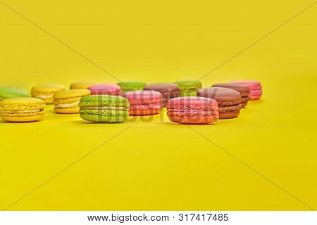 Colored Macaron Or Macaroon, Sweet Meringue-based Confection On Yellow Background. Close-up, Copy Sp