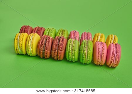 Colored Macaron Or Macaroon, Sweet Meringue-based Confection On Green Background. Close-up, Copy Spa