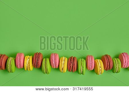Colored Macaron Or Macaroon, Sweet Meringue-based Confection On Green Background. Close-up, Copy Spa