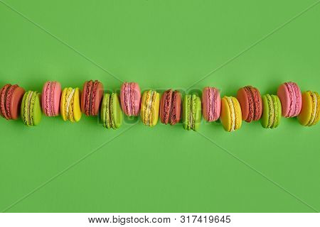 Colored Macaron Or Macaroon, Sweet Meringue-based Confection On Green Background. Close-up, Copy Spa