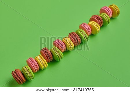 Colored Macaron Or Macaroon, Sweet Meringue-based Confection On Green Background. Close-up, Copy Spa