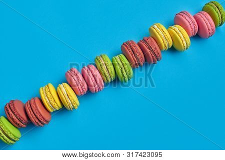 Colored Macaron Or Macaroon, Sweet Meringue-based Confection On Blue Background. Close-up, Copy Spac