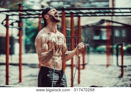 Fitness Man Exercising With Stretching Band. Muscular Sports Man Exercising With Elastic Rubber Band