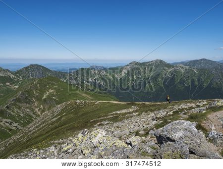 Mountain Landscape Of Western Tatra Mountains With Woman With Bacpack And Dog On Hiking Trail On Bar