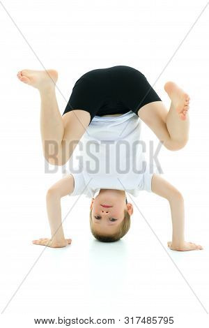 Cute Little Boy Doing A Headstand. The Concept Of Childrens Sports. Isolated On White Background
