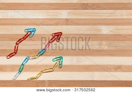 An Arrow Made From Paperclips Pointing Upwards On A Table, Shot From Above.