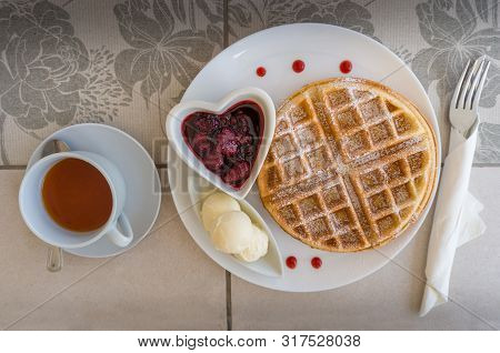 Top View Of Breakfast Table Setting With Belgian Waffles, Ice Cream And Berry Jam With Tea In A Cup.