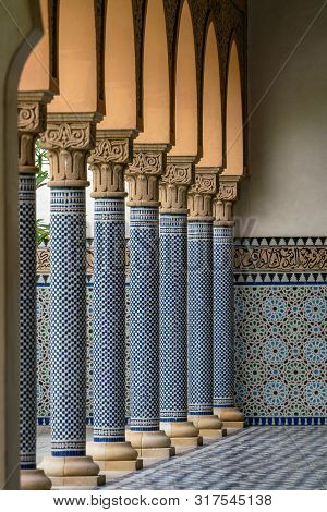 Oriental Looking Columns With Blue Mosaic Pattern And A Tiled Floor With Oriental Patterns