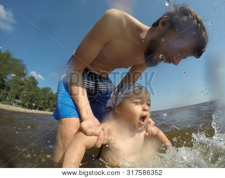 Father In Shorts Bathes His Son In Shorts In The Sea