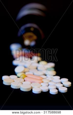 A Bottle Of Spilled Pills On Black Background.levitating Tablets. Tablets On A Dark Background That 