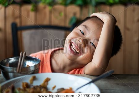 Asian Child Smiling At The Restaurant While Having A Meal