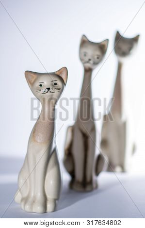 Three Different Size Porcelan Cat Figurines With Long Necks And Expressive Features Sitting Agaist A