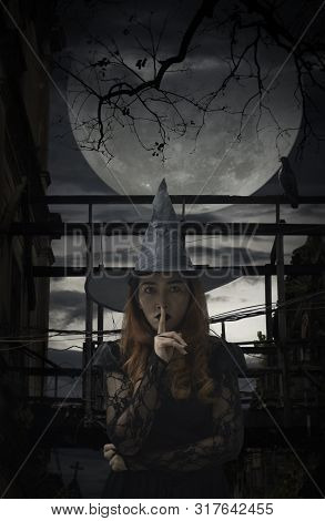 Halloween Witch Showing Silence Sign With Finger Over Lips Standing Over Damaged Old Wooden Bridge, 