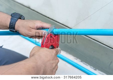 Using A Cutter For Plastic Pipes In The Repair Of Household Water Supply, Plumbing Hand Close-up.