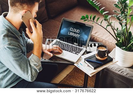 Back View. Bearded Hipster Man Sits At Coffee Table, Uses Laptop With Inscription On Monitor- Cloud