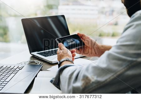 Man Sits In Cafe, Uses Smartphone With Inscription On Screen- Cloud Library. Man Is Looking For Info