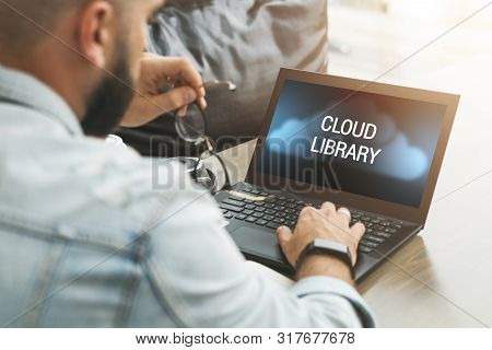 Back View. Bearded Hipster Man Student Sits In Cafe At Table And Works On Laptop With Inscription On